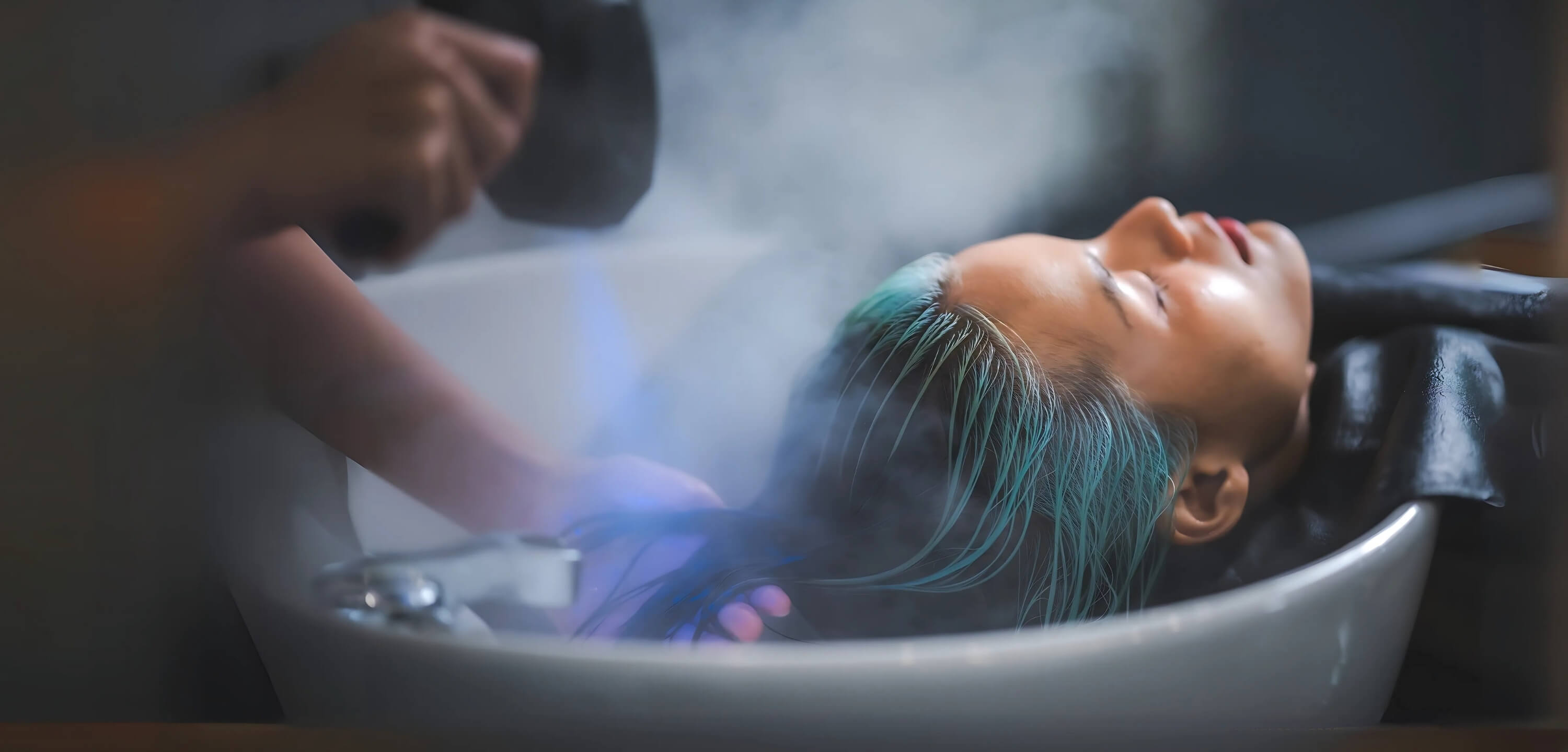 Client receiving a Vital Glow Head Spa steam scalp treatment at the sink, showcasing relaxation and professional care.