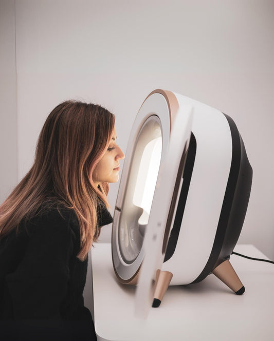 Client using Vital Glow skin analyzer for facial imaging and professional skin analysis.